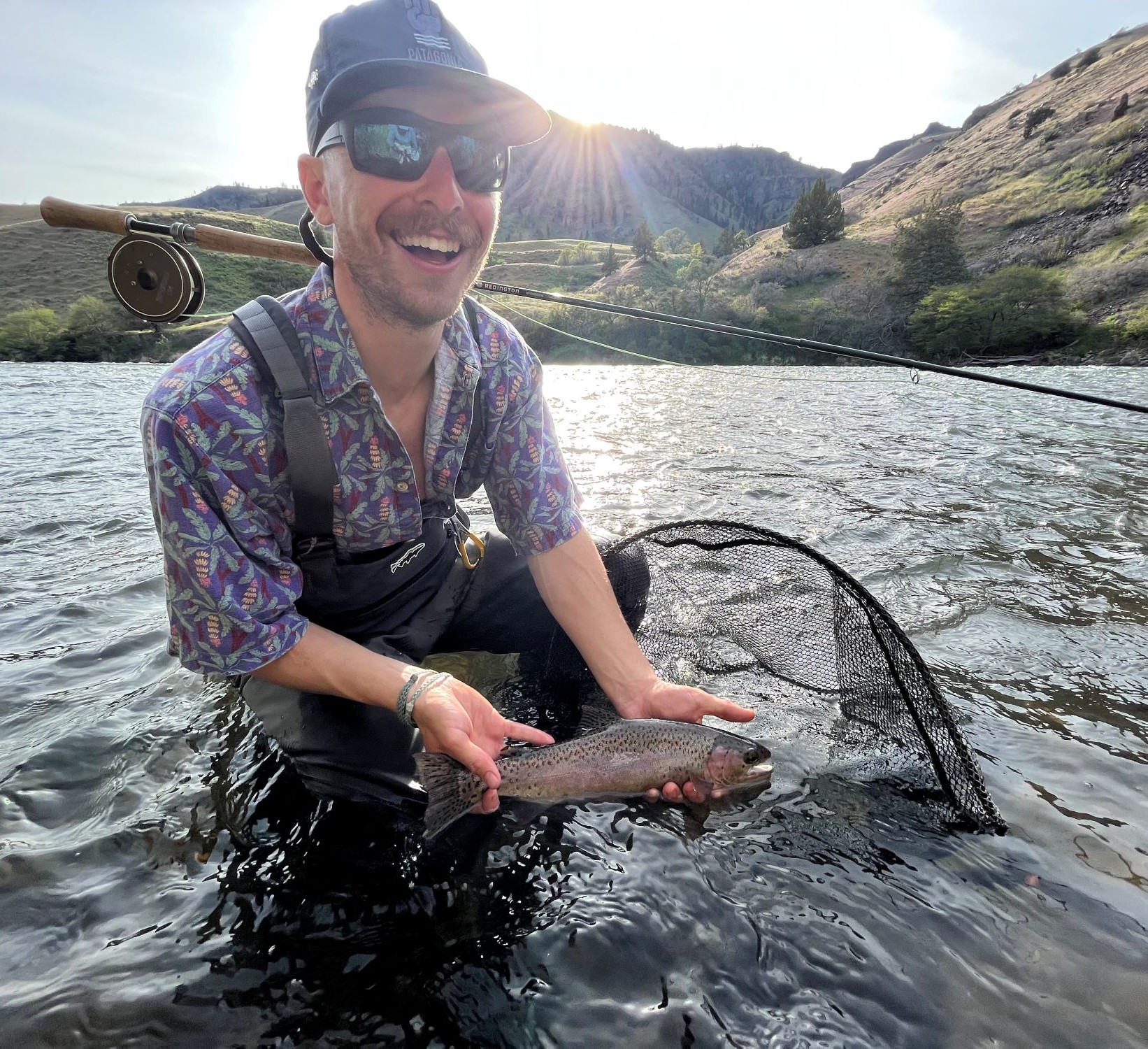 Alex while fly fishing, holding a deschutes redband he caught.