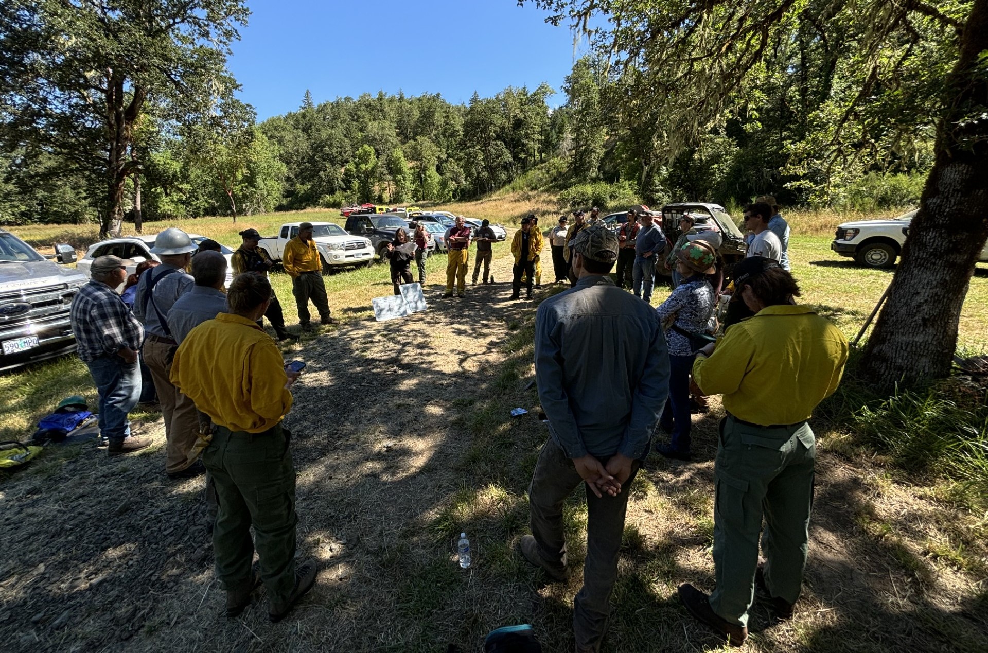 A group of people standing in a circle as they are briefed on safety before the burn.