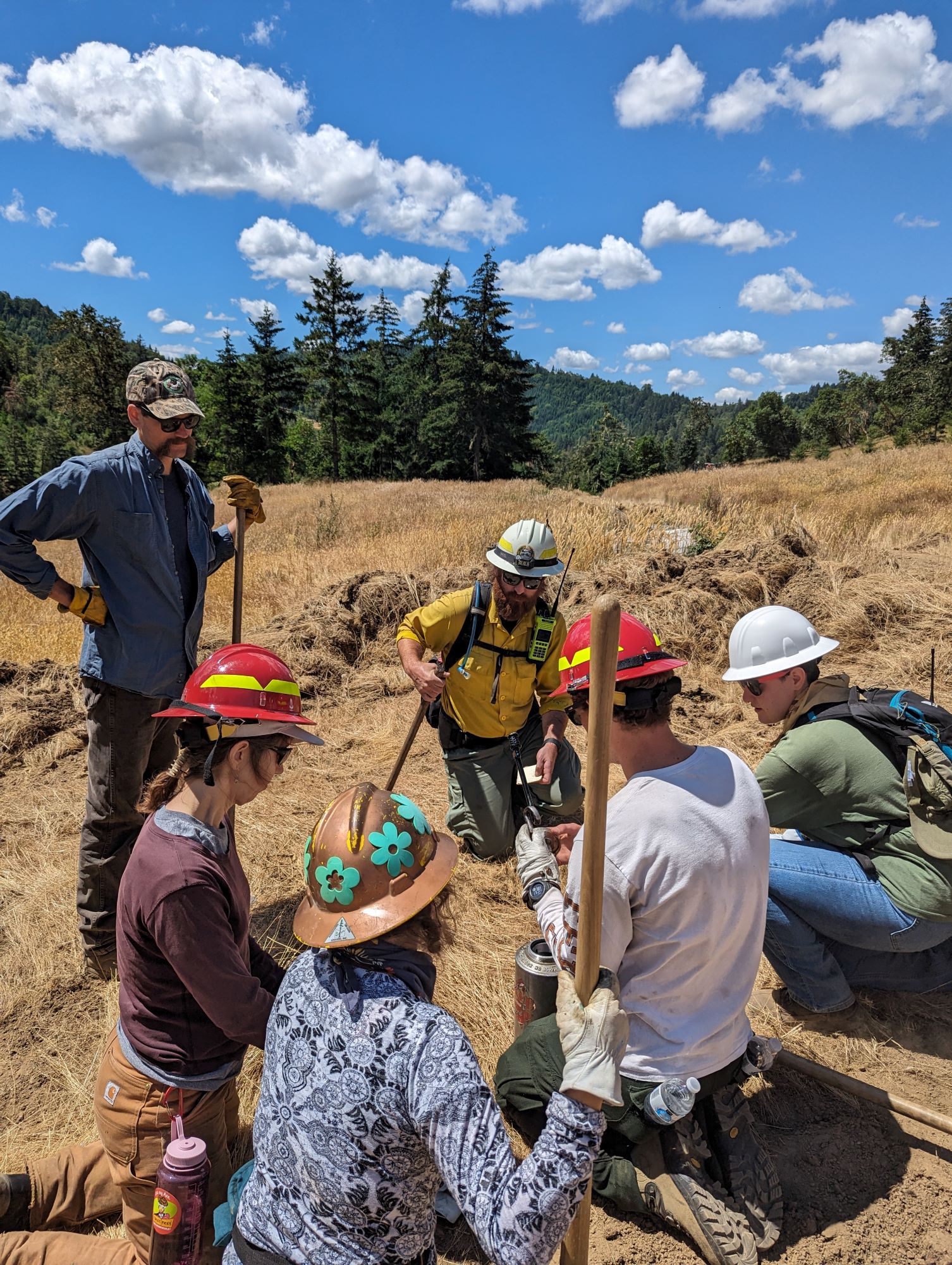 A group of people with helmets in a circle talking.