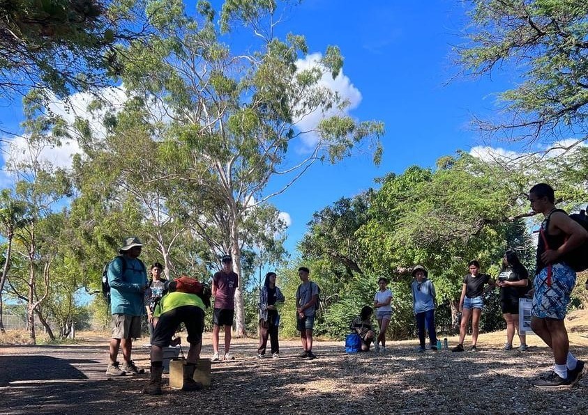 The Project Coordinator is demonstrating the mechanical workings of a DOC 250 trap to
students. Credit: Hui o Hoʻohonua