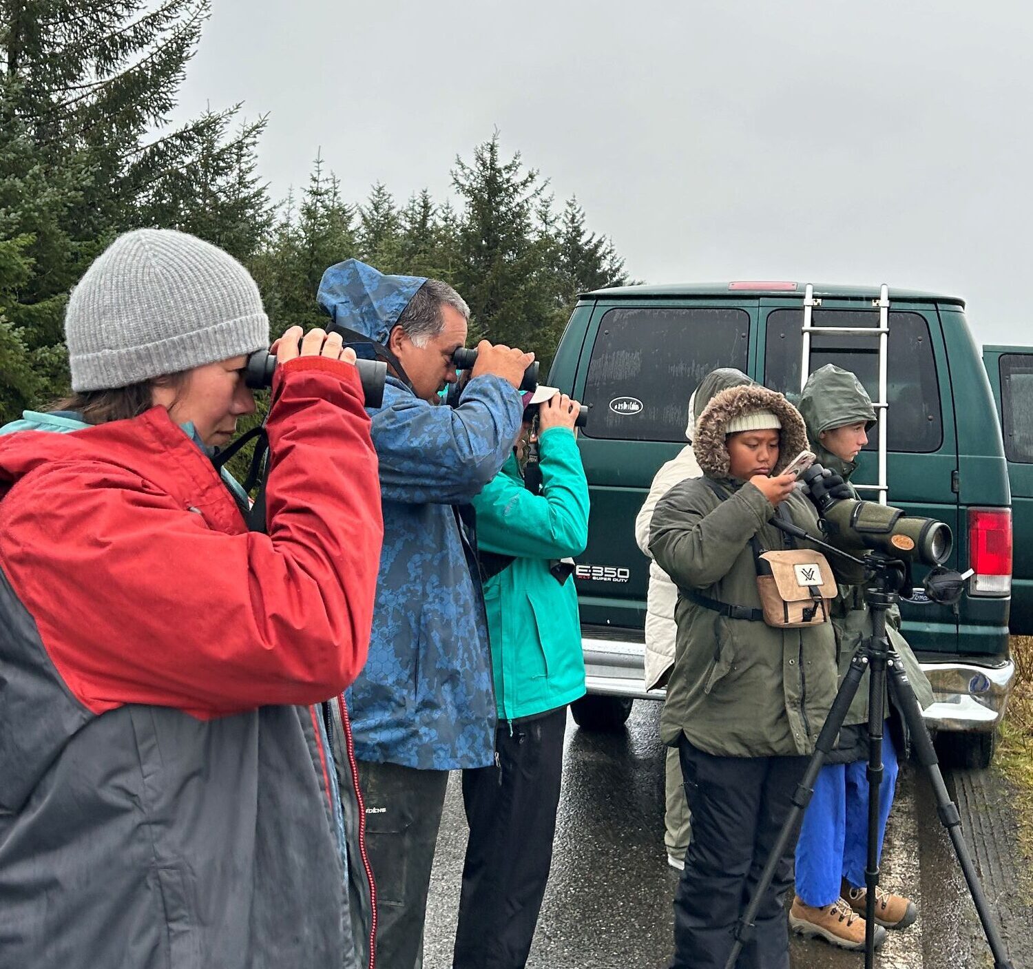 Birdwatchers observing through binoculars in a forest area
