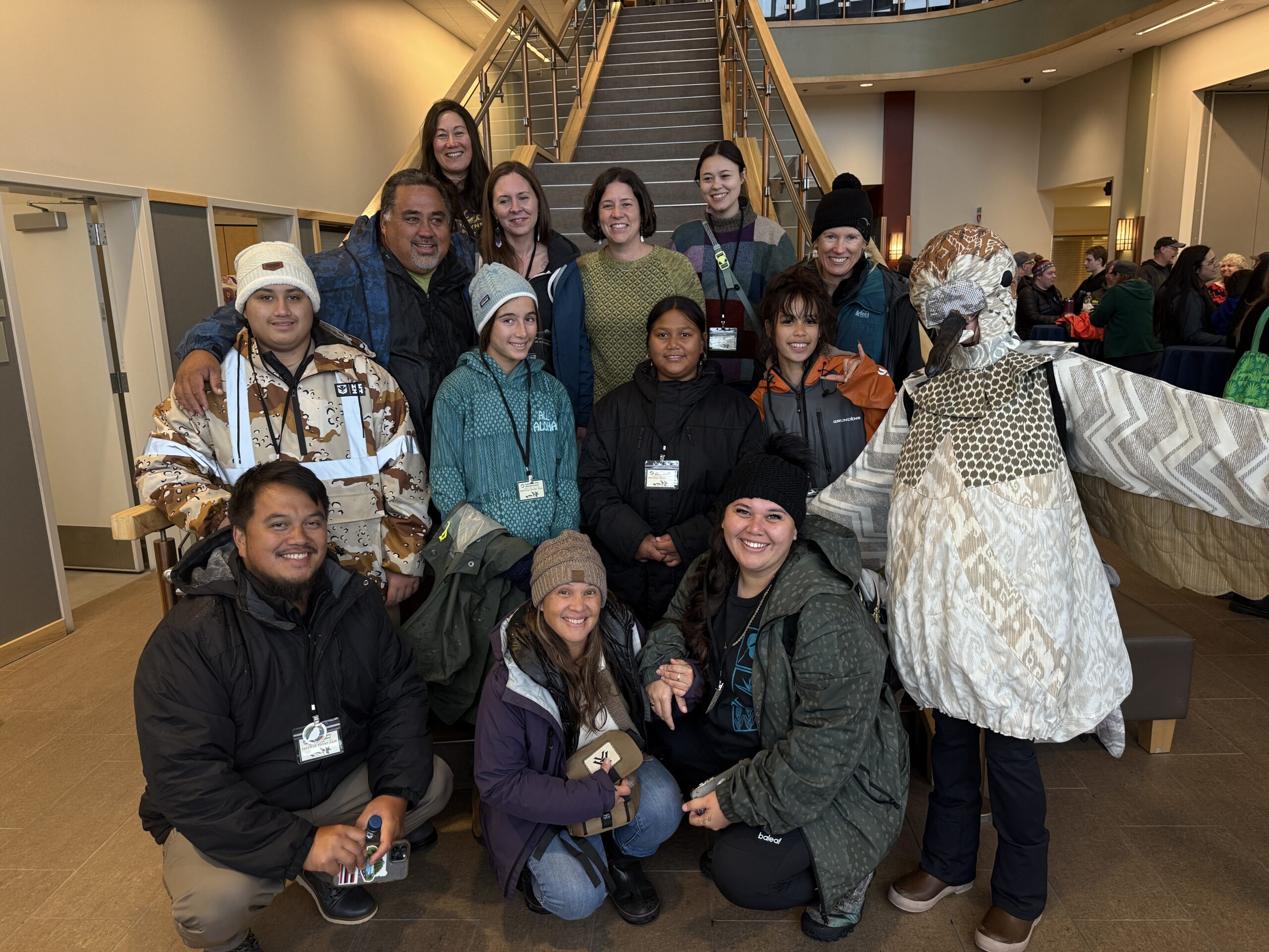 Diverse group gathered at indoor event in winter clothing