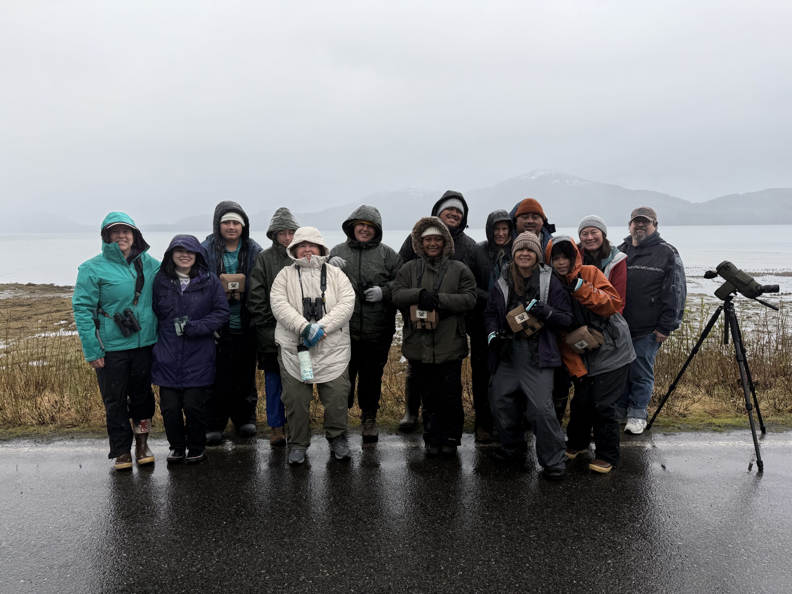 Group of happy birdwatchers in warm clothing by the seaside