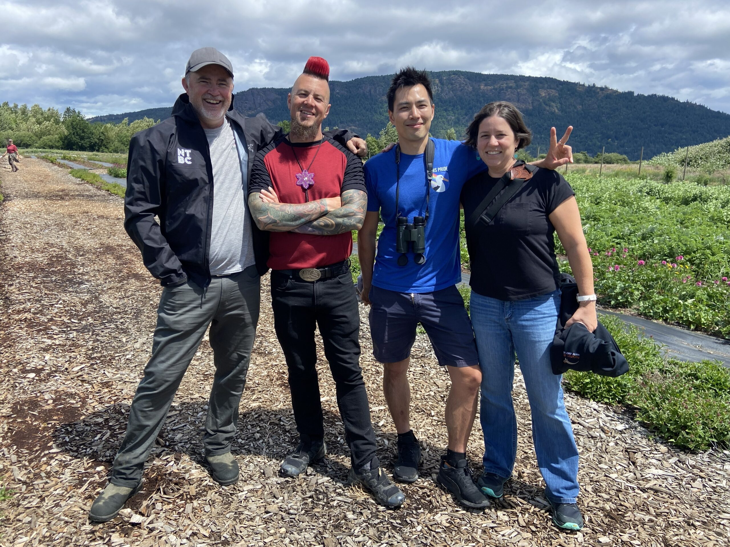 Three men and one woman pose together for a photo while standing in an estuary.