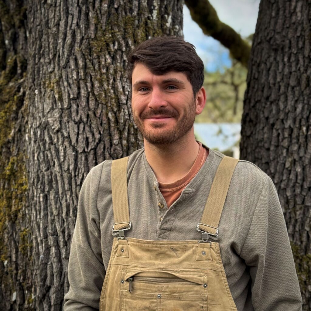 Photo of a man standing in front of a tree